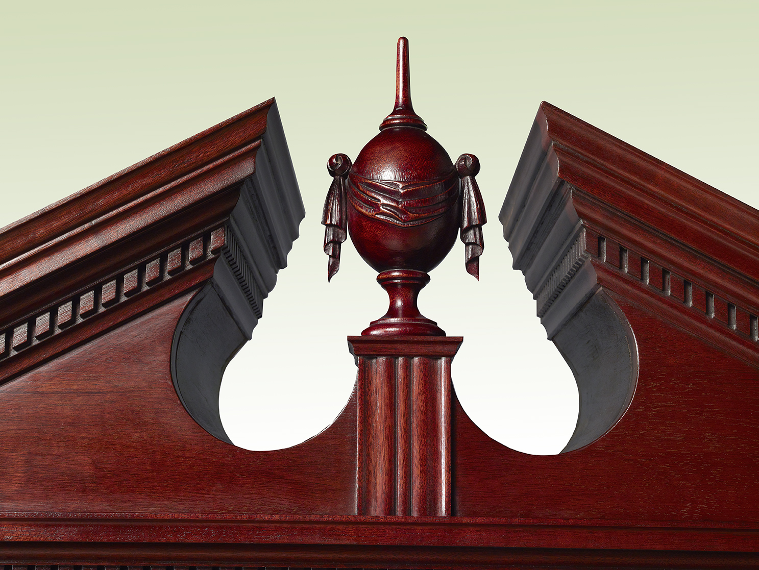 Close-up of a carved mahogany furniture pediment with central cartouche and decorative molding.