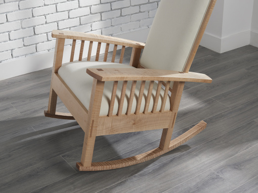 An angled overhead view of the cream wool upholstered seat on a figured maple rocking chair.