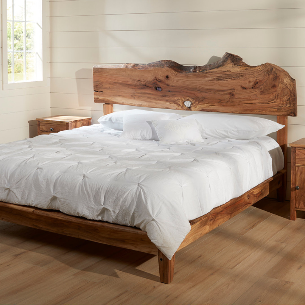 Square A king sized Rustic oak live edge platform bed with crystals embedded in the open knots of the headboard sit in a bright room with matching side tables on either side. A window lights the room from the left side. The bed is dress in a white comforter with white pillows on top.