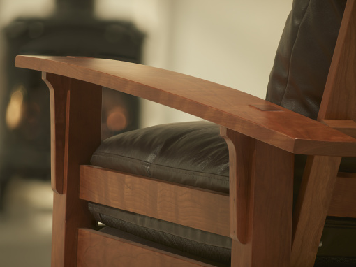 close up of the side arm details on a cherry adjustable back arm chair with peppercorn leather cushions