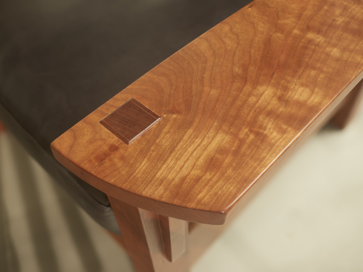 Close up view of the through mortise wedged tenon and arm of the Coorie cherry adjustable back arm chair.