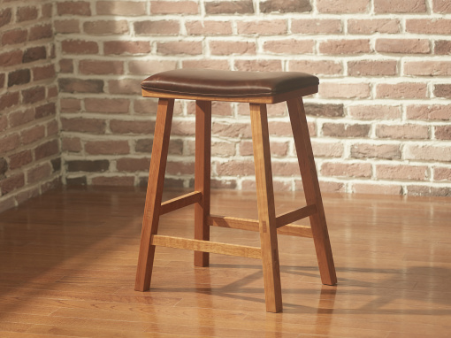 A simple cherry bar stool with a rectangular seat and squared splayed legs with chocolate brown leather upholstery in a room with exposed brick walls and hardwood floor.