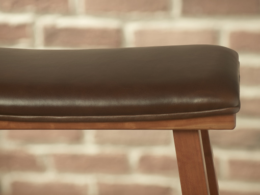 A close up side view of an upholstered cherry kitchen barstool showing the brown leather seat with its piping around the curve of the seat.