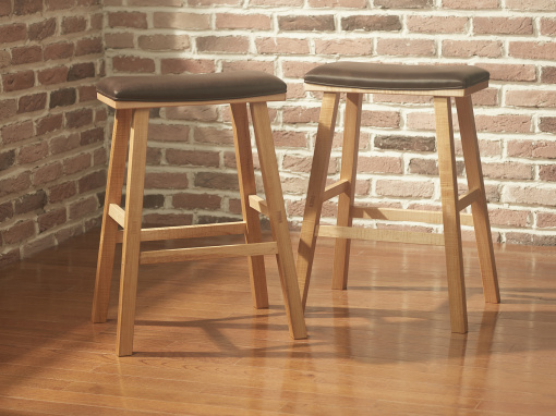 Pair of handmade maple barstools with brown Italian leather seats against brick wall.