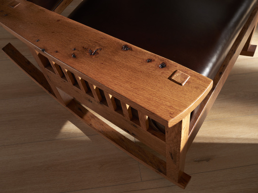 Top view of the arm of a handmade Arts & Crafts-style rocking chair with leather seat and back, crafted from bark-included oak, showing the exposed mortise and tenon joinery.