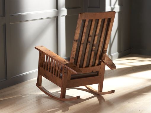 Back view of a handcrafted oak rocking chair with vertical slats and warm natural finish.
