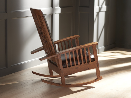 Side profile of a handcrafted rocking chair made from bark-included oak with brown leather seat and back.