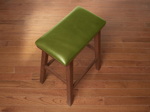 Handmade walnut kitchen barstool with London Apple Italian leather seat on hardwood floor.
