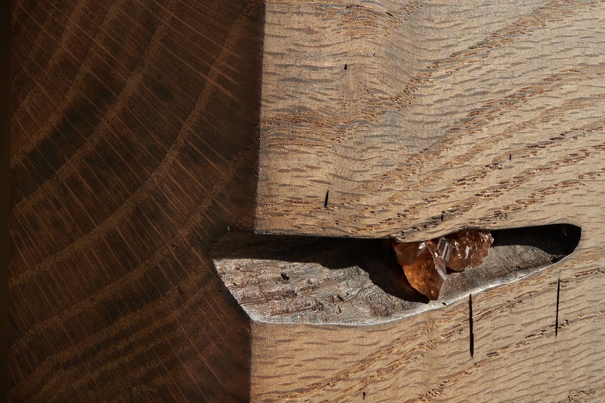 A close up of two gem imperial topaz embedded in a crevice of the live edge headboard of a handmade swamp oak bed, made by Boston craftsman Thomas J. MacDonald