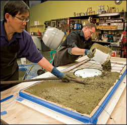 Concrete manufacturer and designer Fu-Tung Cheng brings shape to a countertop as he smooths concrete mix into a mold with a helper. Photo by Matthew Millman, courtesy of Taunton Press.