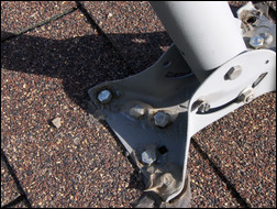 This typical satellite dish install has lag bolts driven straight through the roof, which often result in leaks and roof damage. Photo courtesy of Commdeck.